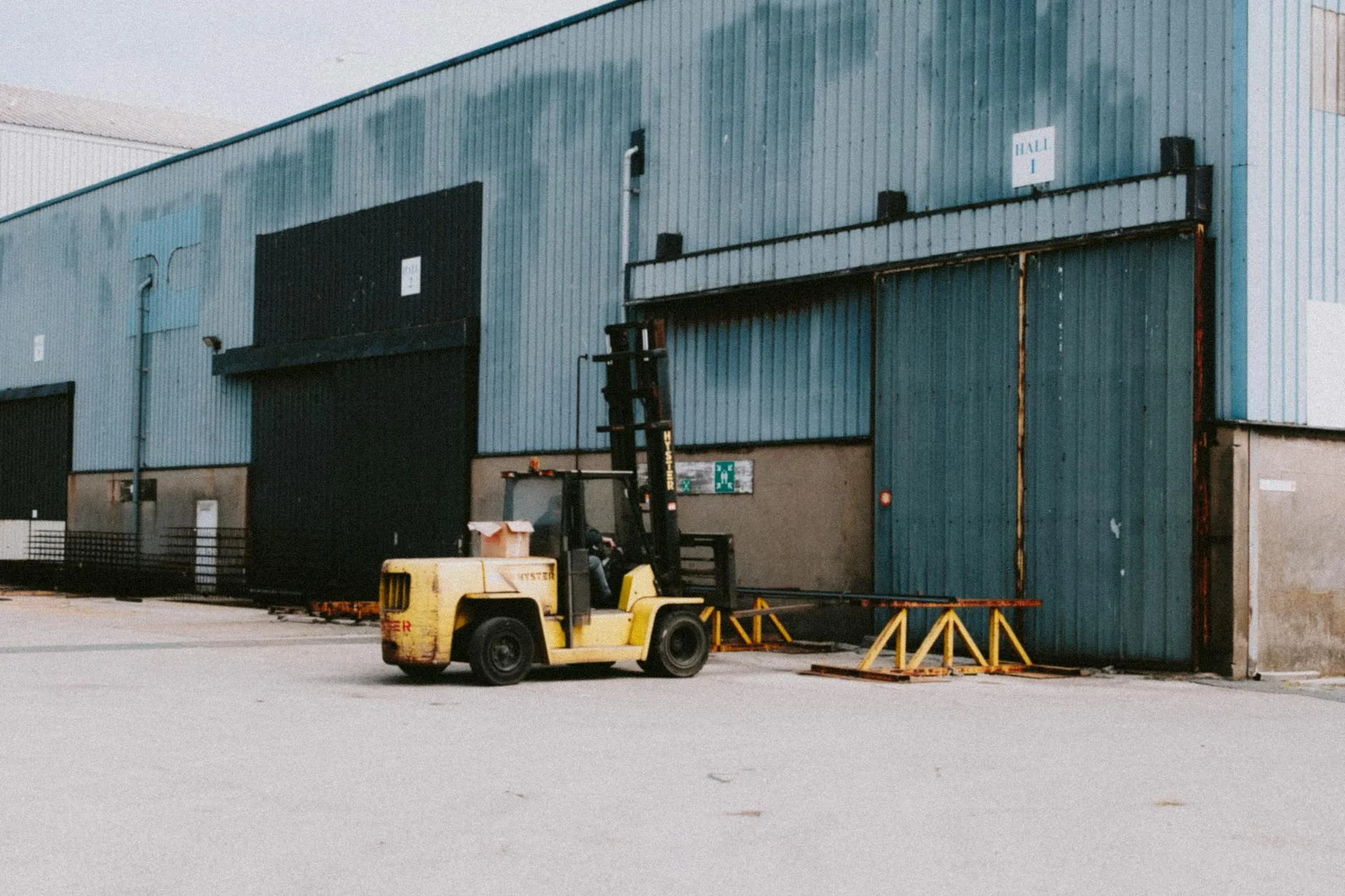 Teknisi memeriksa dan memperbaiki forklift di area industri MM2100, memastikan operasional lancar.
