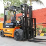 Forklift Nissan model terbaru berwarna merah, sedang mengangkat palet di gudang industri.