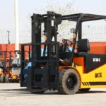 Forklift dengan baterai lead acid menampilkan panel kontrol dan roda besi, siap mengangkat beban berat di gudang.